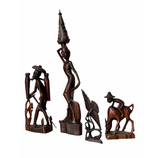 An expressive collection of four carved wooden sculptures featuring rich brown tones, dramatic dark grain, and intricate...