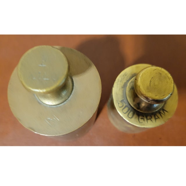 A set of 5 solid brass antique scale weights ranging from 50 grams to 1 kilo, with a hardwood holder. (100, 200, 500...