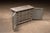 Low, wide workshop cabinet in heavily worn gray paint, revealing layers of earlier finish and raw wood beneath. The case...