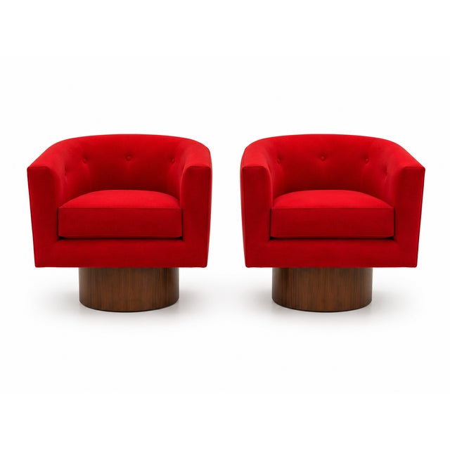 Pair of modern club chairs with walnut base. The chairs swivel. The chairs are done in a red chenille.The bases are walnut...
