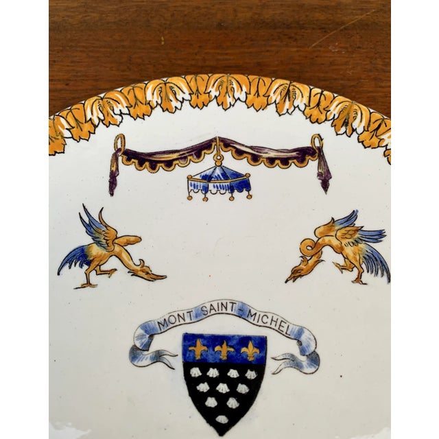 A gorgeous vintage Neoclassical style wall plate from Mont Saint Michel featuring stylized dolphins, birds, swags, and a...