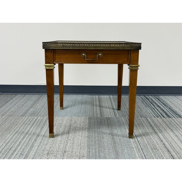 This is a vintage French Louis XVI-style accent table by Baker Furniture, featuring book-matched walnut grain veneers and...