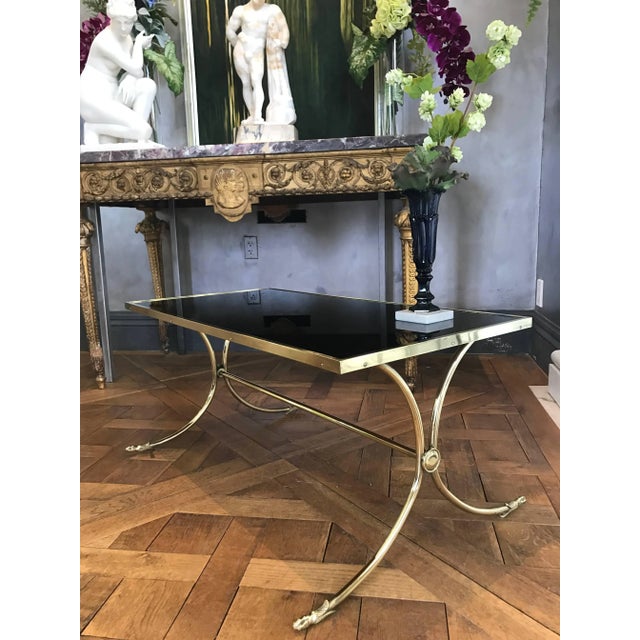 This elegant neoclassical Jansen Style French Coffee Table is made of a solid brass base and polished to a high luster....