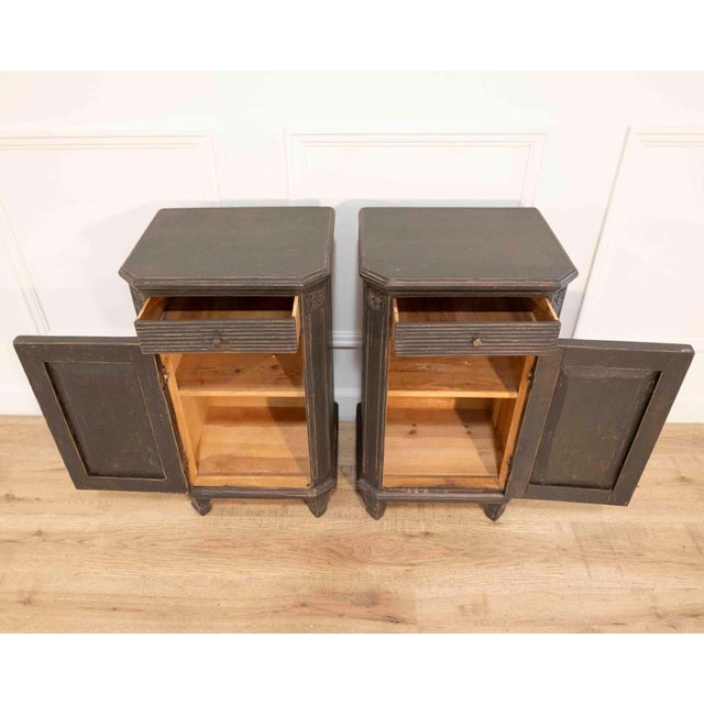 A well-matched pair of Swedish nightstands dating to circa 1880, crafted in pine and retaining their original black-...