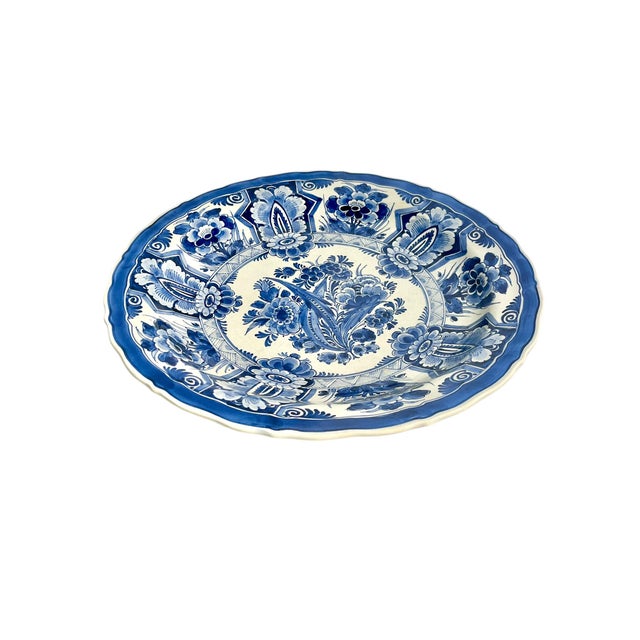 Vintage Delft large size charger bowl. Has a wire for hanging on the wall. Creamy white with blue flowers. Center features...