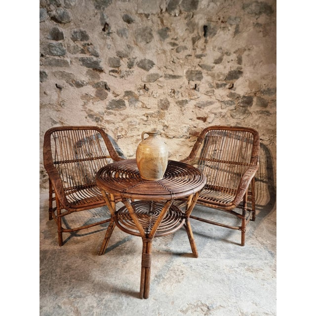 Vintage rattan lounge set dating from approximately 1930–1950, consisting of two lounge chairs and one matching round...