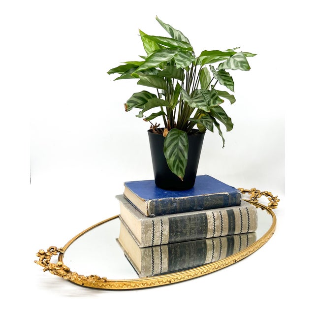 Elegant vintage oval mirrored tray with a richly detailed gilt metal frame and ornate floral handles at each end. Lovely...