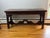 featuring rich dark wood construction and intricate hand-carved detailing throughout. The rectangular top is supported by...