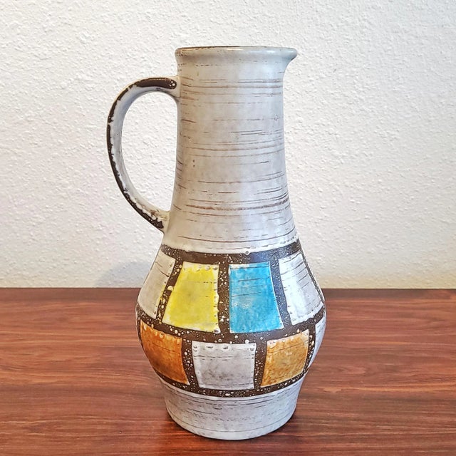 A tall and colorful, early '60s pitcher-form vase from JASBA KERAMIK. A dark brown undercoat is topped with a light gray...