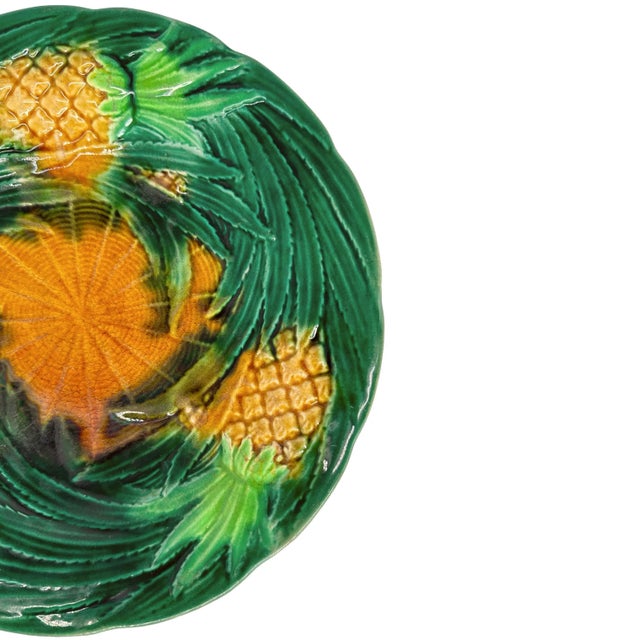 A George Jones Majolica Dessert Plate, with relief-molded pineapples and swirling green-glazed leaves, the center with...