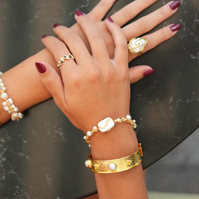 Make a statement with the Pearl & Gold Boho Chic Cuff Bracelet, a stunning piece adorned with intricate antique designs....