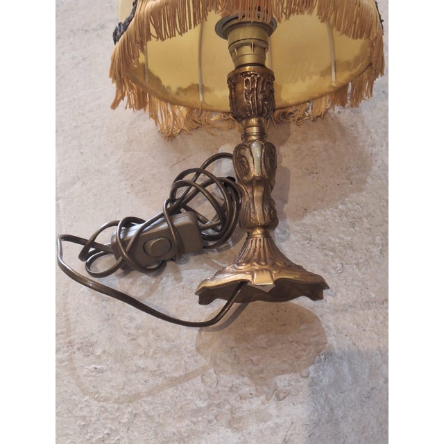 Vintage boudoir table lamp featuring a beautifully detailed brass-tone base paired with a cream satin shade adorned with...