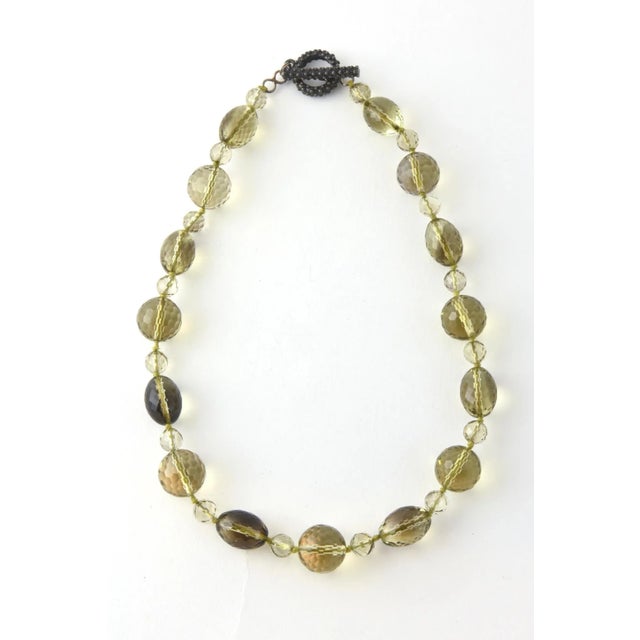 Necklace of faceted glass beads in shades of brown and yellow. Knotted between each bead. Beaded toggle closure with a...