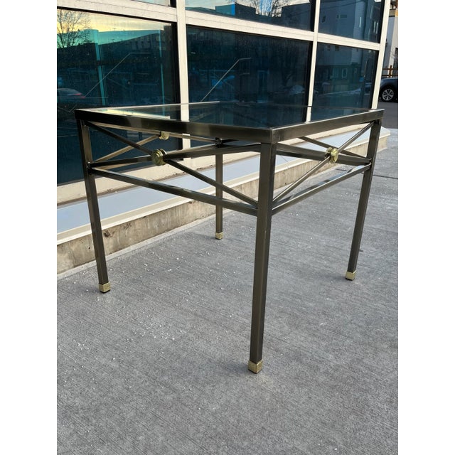 Modern gunmetal end table of classic x form design elements having brass medallions with capped feet and inset glass top,...