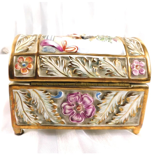 This is a porcelain Capodiamonte storage or trinket box. It is rectangular with a hinged domed lid with some nudity on it....