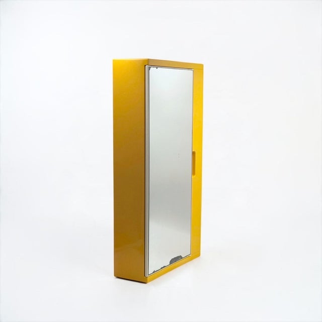 A yellow wall-mounted mirror cabinet designed by olaf von bohr for gedy in italy during the 1970s. the design combines a...