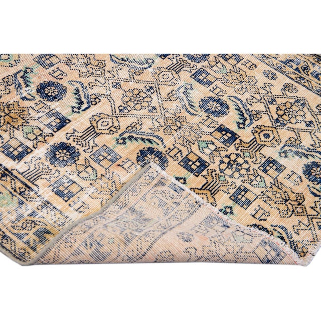 Beautiful vintage distressed hand-knotted wool runner with a beige field. This Persian rug has blue, Ivory, and brown...