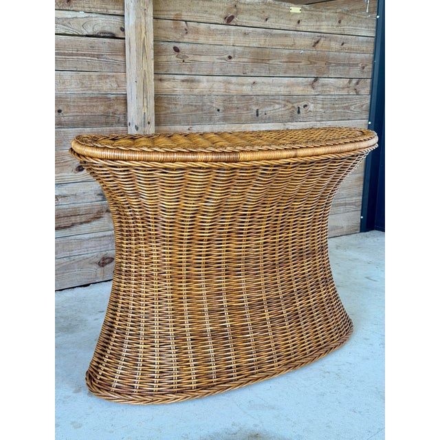Stunning vintage rattan console table featuring an elegant hourglass silhouette and beautifully detailed braided trim....
