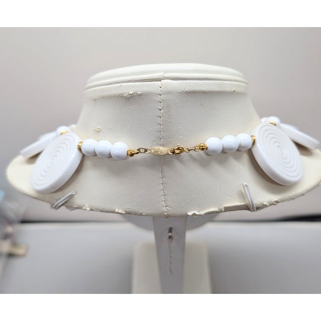 1985 goldtone round white resin spiral plaques with round white resin spacers necklace with fold over clasp. Marked...