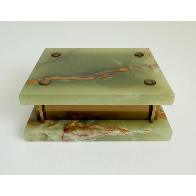 A 1940s-1950s Art Deco-style box with a hinged lid. The lid and base are made of green onyx with gold and red veining; the...
