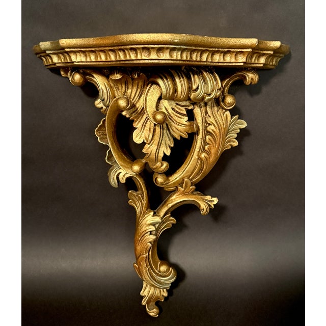 This elegant pair of carved wall brackets is crafted in giltwood and richly ornamented with flowing Rococo-style...