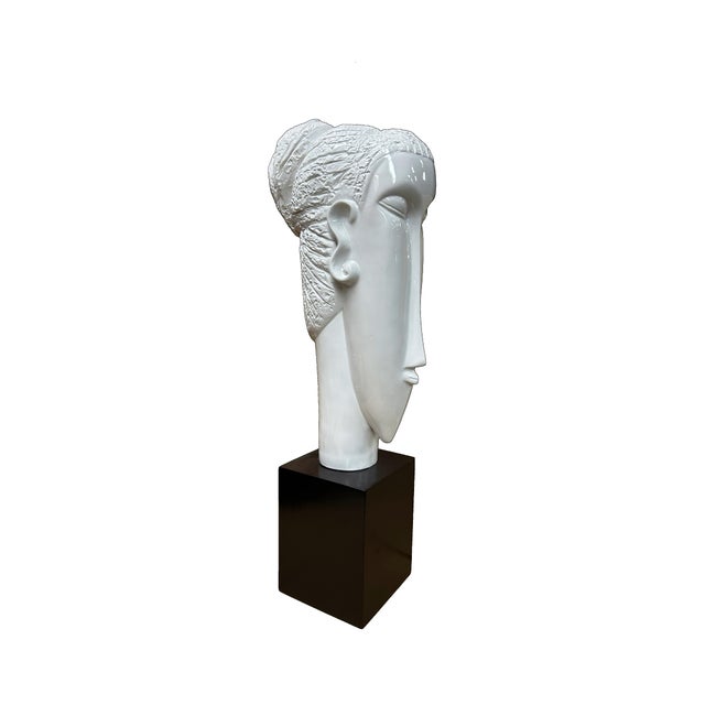 This sculpture presents a stylized, elongated head crafted from high-quality fiberglass, finished in a brilliant, glass-...