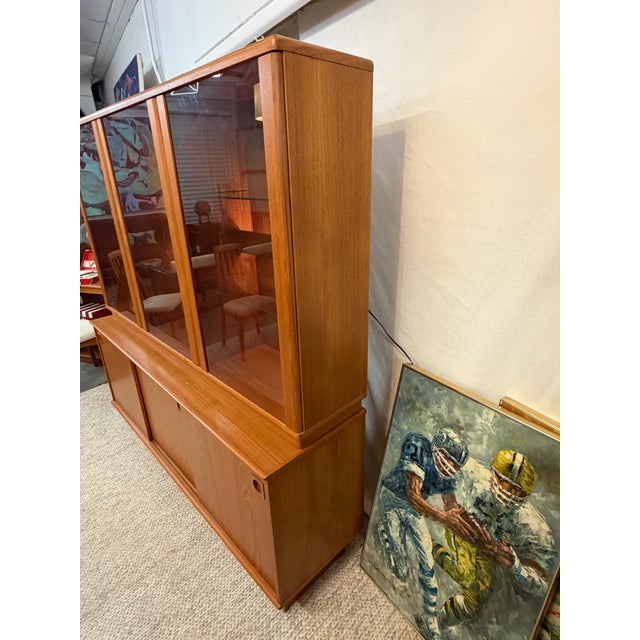 This 1970s Danish modern teak wall unit was made by Dyrlund and features their signature thick solid wood trim profile....
