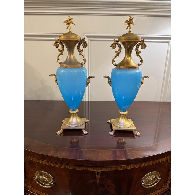 A refined and elegant pair of antique French turquoise blue opaline urns, richly mounted in gilt bronze (ormolu), dating...