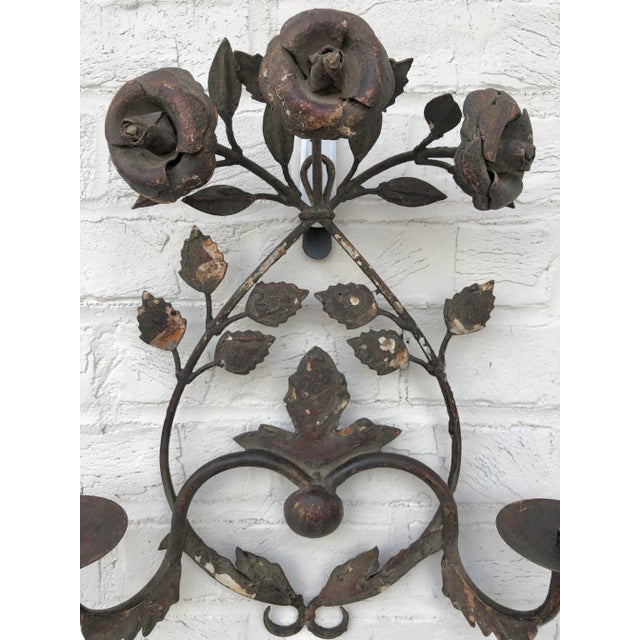 Beautiful and unique, this iron wall sconce is sure to make a statement in your home. Adorned with cast iron rosettes and...