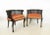 Tailored stately pair of ebonized bergères. These armchairs feature a caned barrel back including a rounded edge over a...