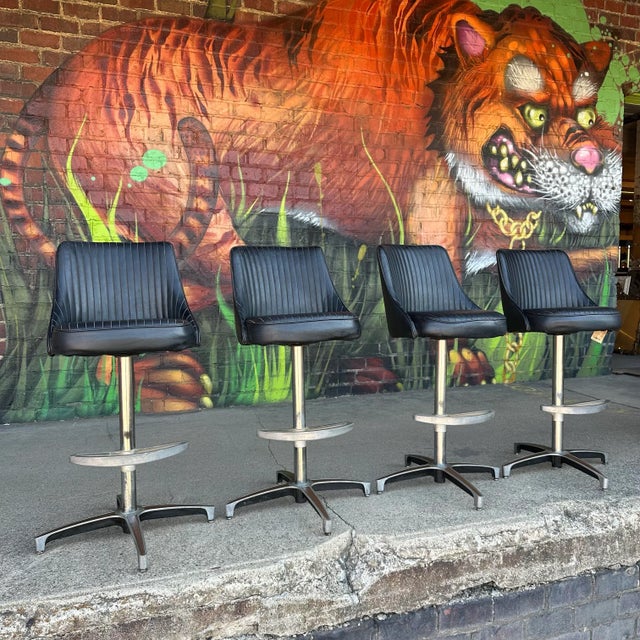 Set of 4 swivel bar stools from ChromCraft. The seats are channeled black vinyl and the bases are constructed of steel....