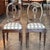 Oval backs with a pierced centre splat and a small carved flower at the top, over upholstered seats in a cream and brown...