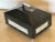 A hinged and lidded box comprised of black granite-like stone and another white stone contrast. The lid has a nickel-...