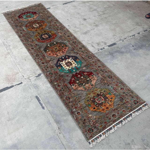Tribal Runner Rug, hand-knotted from wool and filled with rich color. Featuring multicolor medallions on a soft gray...