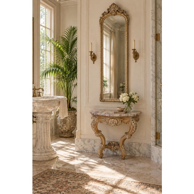 A petite Spanish reproduction demi-lune console table with a richly veined marble top and sculptural carved base in a warm...