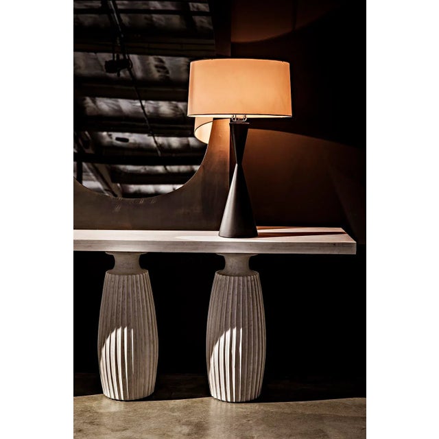A crisp white oval shade tops a simple black metal base, and is itself topped with a coordinating metal finial, in this...