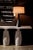 A crisp white oval shade tops a simple black metal base, and is itself topped with a coordinating metal finial, in this...