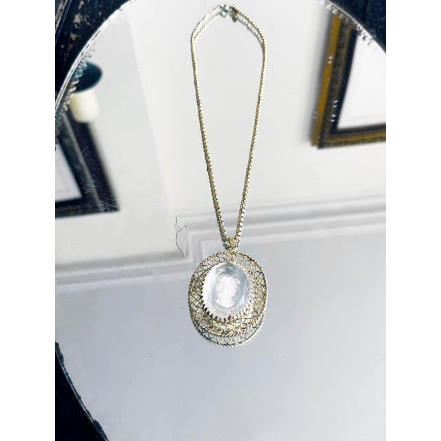 Vintage Whiting & Davis necklace from the 1930s featuring a clear glass intaglio cameo set in a gold-tone filigree frame....