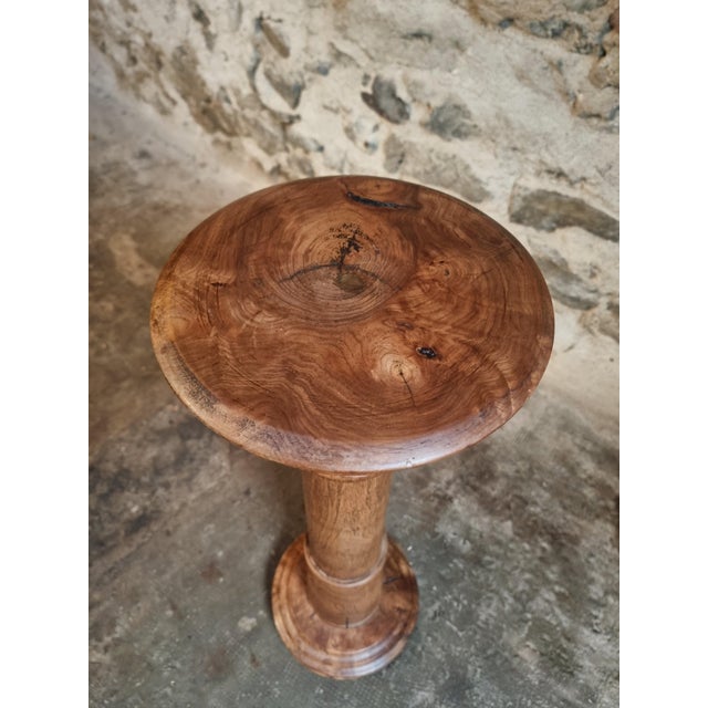 This antique French pedestal, dating from around 1900, is made from solid elmwood and features a finely turned column with...
