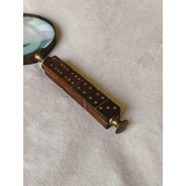 A distinctive vintage magnifying glass with a carved wooden handle inspired by a dice, finished with small brass coloured...