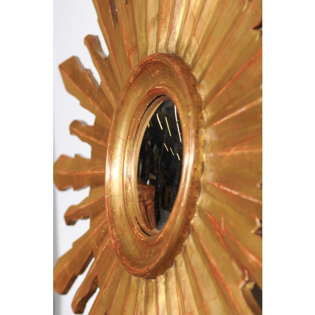 A large vintage French sunburst mirror from the mid-20th century, with convex mirror and radiating rays. This captivating...