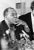 This striking black-and-white photograph captures jazz legend Louis Armstrong during a candid moment at a press event in...