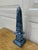 A beautifully proportioned marble obelisk in richly veined shades of blue and cream. The sculptural silhouette and...