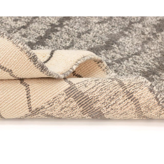 Unlock the essence of Berber culture with this handcrafted Ivory and Black wool rug. Zigzag lines and chevrons blend...