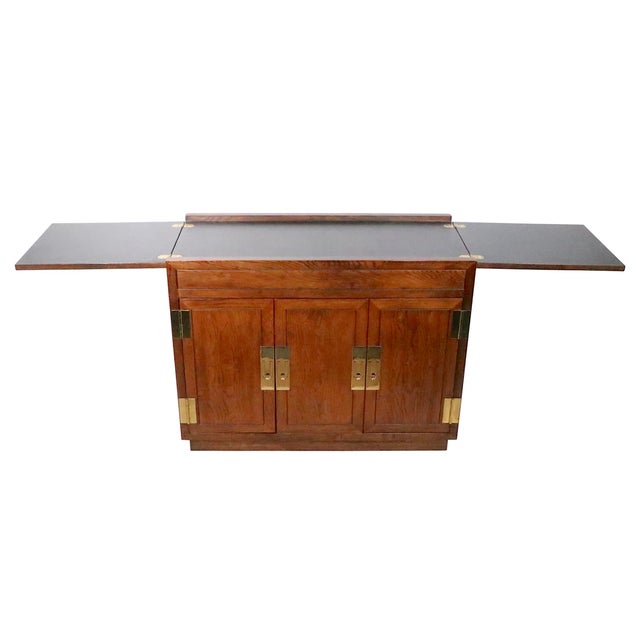Chic Campaign style cabinet dry bar, by Henredon, circa 1970/90's. This voguish cabinet features stylish brass hinges and...