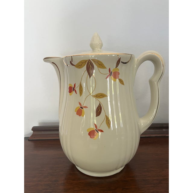 A classic Hall China covered coffee pot in the beloved Jewel Tea Autumn Leaf pattern, featuring a warm ivory glaze...