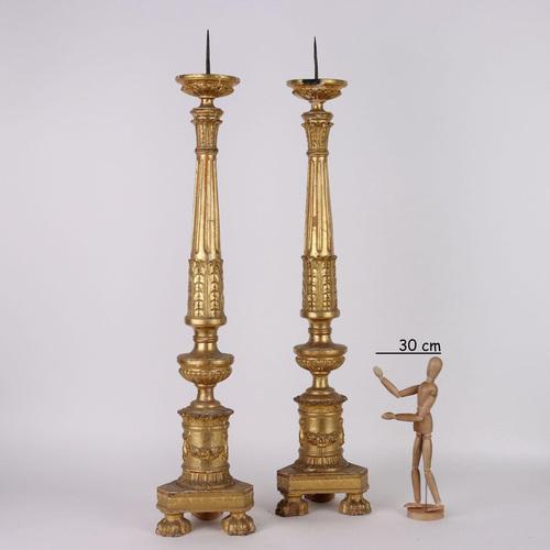 Pair of carved and gilded wooden torch holders with repeated motif decorations, flowered festoons, pods and grooves. This...