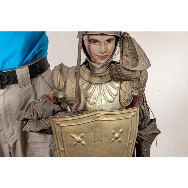A large antique carved Italian wood marionette dressed as an armored knight, wearing a plumed helmet, metallic...