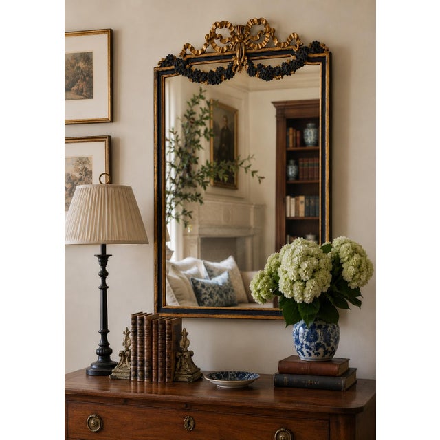 An elegant Italian giltwood mirror featuring carved floral swags, ribbon cresting, and a beautifully muted blue painted...