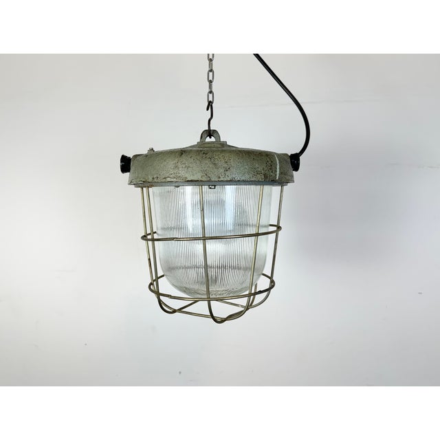 Industrial factory hanging lamp made by Polam Wilkasy in Poland during the 1960s.It features a cast iron top, a striped...